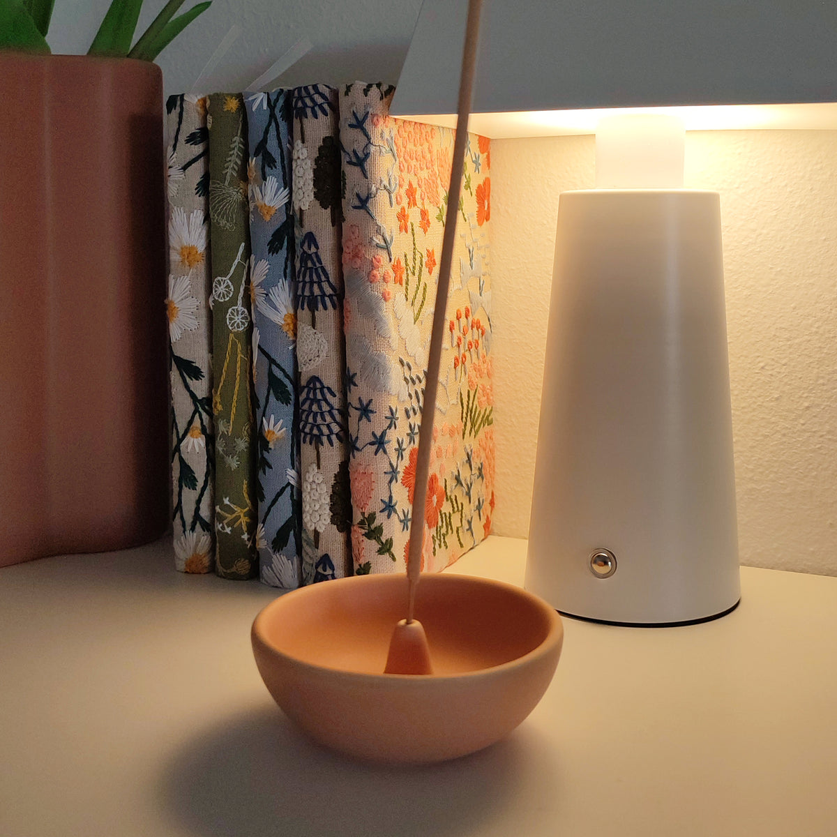 Porta incenso Bowl, con incenso, ambientata in studio con quaderni, lampada a led e vaso, BECCA