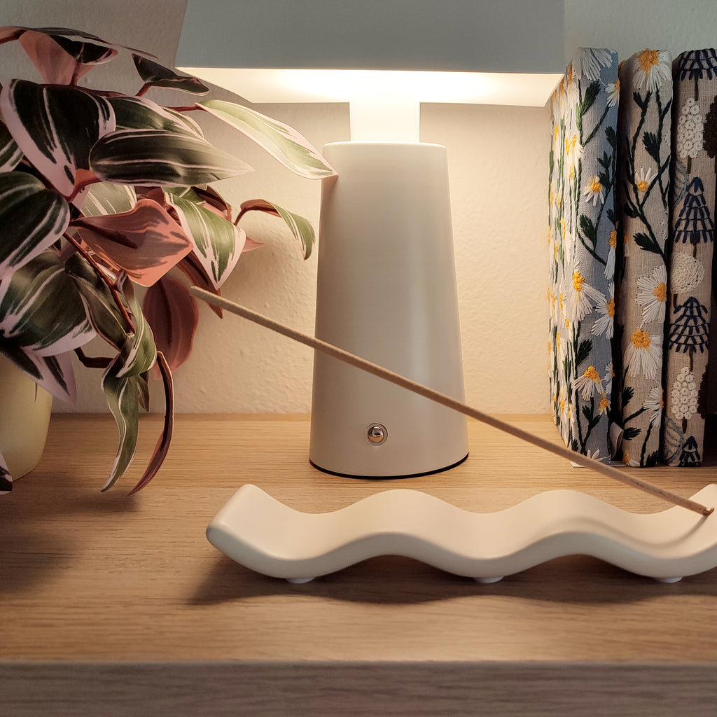 Porta incenso Wave bianco, con incenso, vista laterale ondulata, con luce soffusa, BECCA