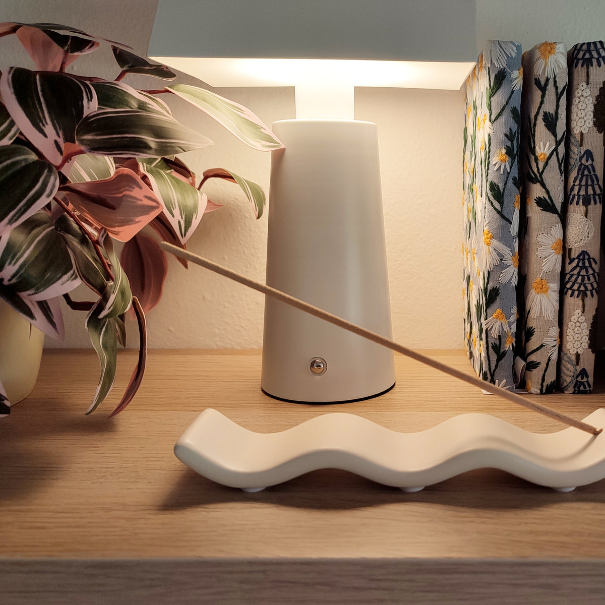 Porta incenso Wave bianco, con incenso, vista laterale ondulata, con luce soffusa, BECCA