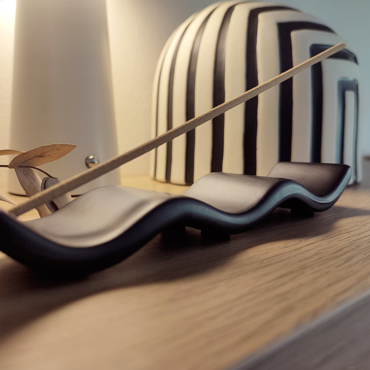 Porta incenso Wave nero, su ripiano con vaso a righe bianco e nero, BECCA