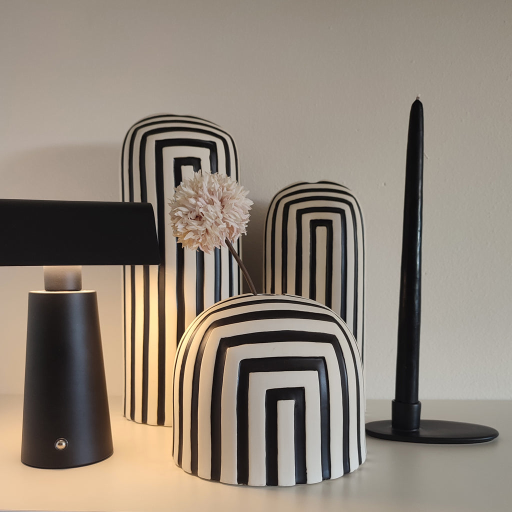 Vasi Black&White, serie in ceramica bianco e nero, su mobile chiaro, con lampada nera e portacandela nero, fiore bianco, BECCA