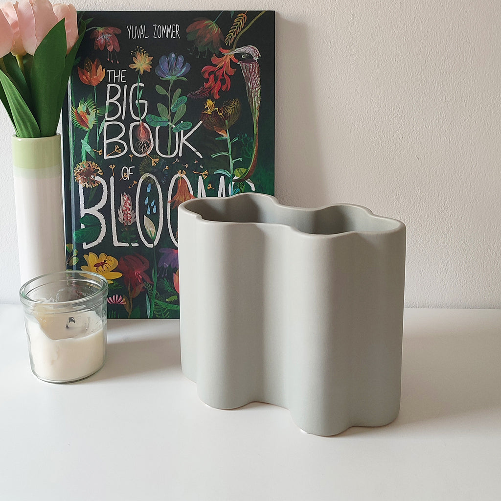 Vaso Onda grigio, in ceramica, su mobile chiaro, candela fiori e libro botanico, BECCA