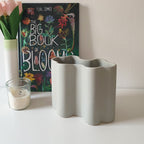 Vaso Onda grigio, in ceramica, su mobile chiaro, candela fiori e libro botanico, BECCA