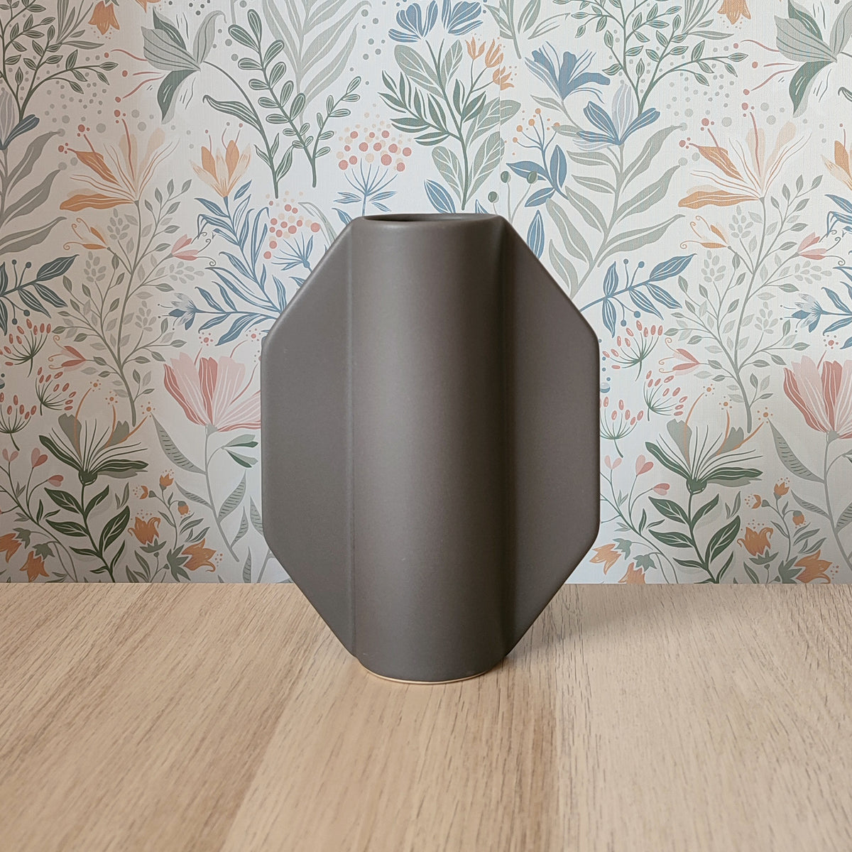 Vaso TOO POT grigio forma ottagonale, vista frontale su sfondo carta da parati botanica, BECCA