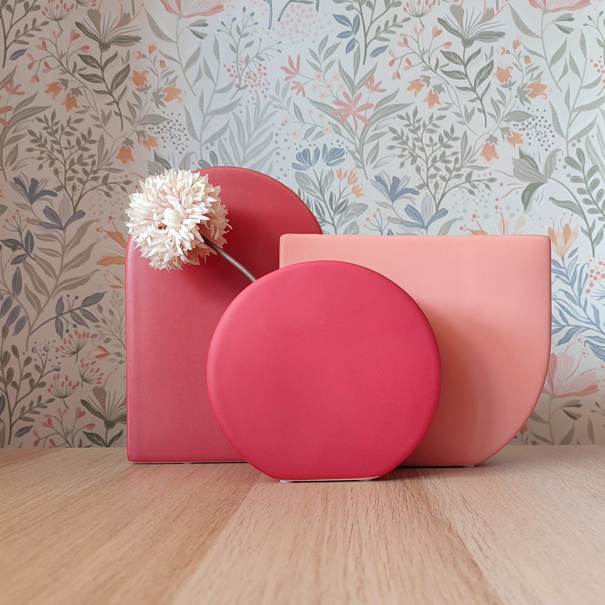 Collezione vasi BERRY taglia S, M e L in tonalità rosa, rosso e lampone su piano in legno con sfondo floreale, BECCA