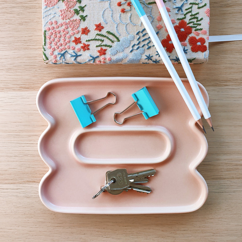 Vassoio Jewe, in ceramica rosa, vista dall'alto, con quaderno matite chiavi, BECCA